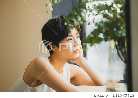 窓辺で夕陽を見る女性　 111570415