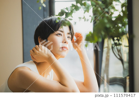 窓辺で夕陽を見る女性　 111570417