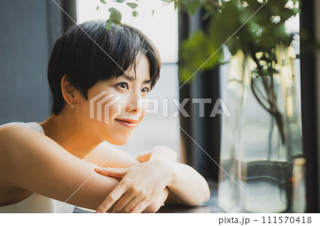 窓辺で夕陽を見る女性　 111570418