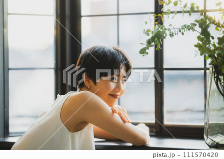 窓辺で夕陽を見る女性　 111570420