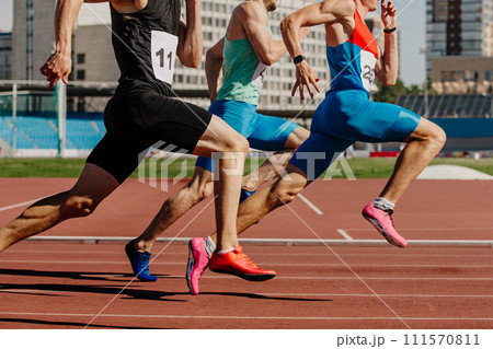 three male athletes sprinting on red track, muscles taut, competing fiercely 111570811