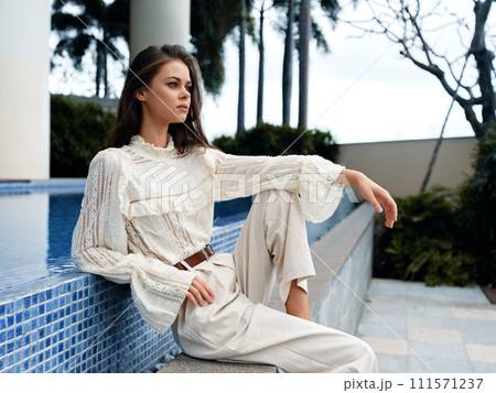 Stylish Lady Posing in a Pretty White Dress, Embracing the Beauty of a Sunny Summer Park 111571237