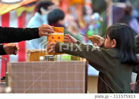 縁日の露店　ポテトチップスを買ってもらう女の子　 111575913