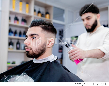 Black hair barber cutting facial hair on forehead, jaw, and neck 111576281