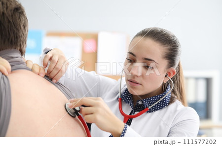 Doctor listening to patient back with stethoscope 111577202