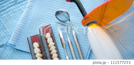 Dental instruments and dentures lying on sterile medical napkin in clinic closeup Dental instruments and dentures lying on sterile medical napkin in clinic closeup 111577253