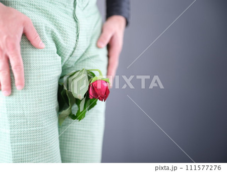 Withered rose flower sandwiched between man legs closeup 111577276