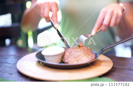 Woman eating potato pancakes with sour cream sauce from frying pan using knife and fork closeup. Woman eating potato pancakes with sour cream sauce from frying pan using knife and fork closeup. 111577282