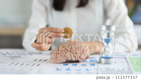 Business woman holding bitcoin coin in front of brain mockup and hourglass closeup 111577337