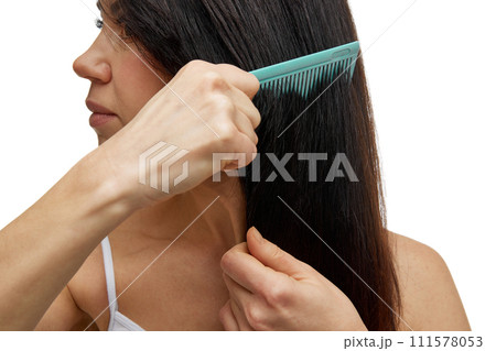Close up photo of beautiful middle aged woman brushing her healthy and silky long hair looking away against white studio background. Close up photo of beautiful middle aged woman brushing her healthy and silky long hair looking away against white studio background. 111578053