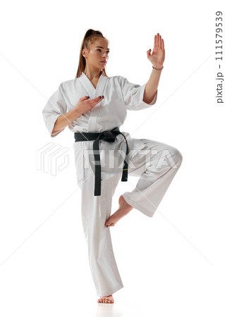 Balance. Master black belt Tae Kwon Do teacher in uniform standing on one leg isolated over white background. Balance. Master black belt Tae Kwon Do teacher in uniform standing on one leg isolated over white background. 111579539