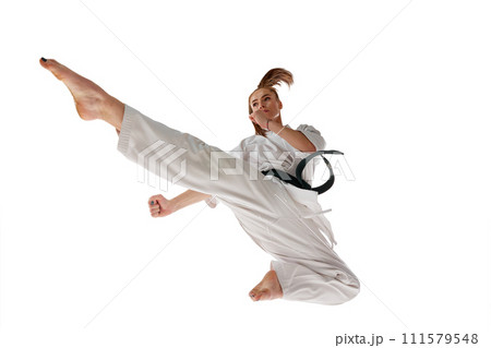 Rear view. Woman professional karate fighter jumping and performing kick in action isolated over white background. Rear view. Woman professional karate fighter jumping and performing kick in action isolated over white background. 111579548