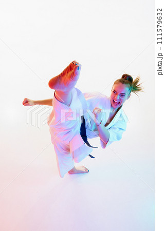 Top view portrait of female karate fighter, teacher performing high kick isolated over white studio background. 111579632