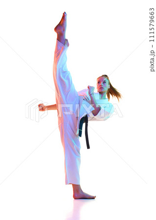 Master black belt Tae Kwon Do fighter in uniform with black belt show high kick pose in neon light against white background. 111579663