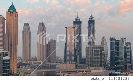Cityscape with skyscrapers of Dubai Business Bay and water canal aerial night to day timelapse. Cityscape with skyscrapers of Dubai Business Bay and water canal aerial night to day timelapse. 111581288