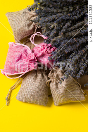 Dried lavender flowers and sachets on a yellow background. Dried lavender flowers and sachets on a yellow background. 111581582