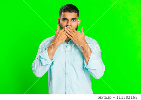 Frightened Indian man closing mouth with hands refusing to tell terrible secret, unbelievable truth 111582165