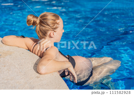 Radiant and relaxed, a pregnant woman finds serenity while enjoying the refreshing embrace of the pool, embracing moments of buoyant joy during pregnancy 111582928