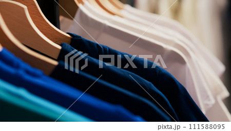 Selective focus of hangers and racks filled with basic shirt, empty modern boutique with fashionable clothes. Shopping centre equipped new fashion collection waiting for customers. 111588095