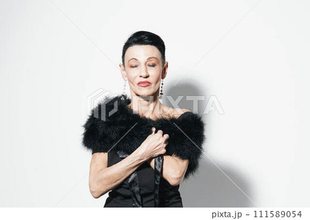 Elegant woman in black dress with fur stole posing for camera in stylish fashion shoot 111589054