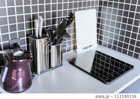 1人暮らし用の小さい1口のIHコンロのあるタイル張りで調理器具の置かれたキッチン 111590136
