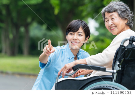 車椅子の高齢者と若い介護士 111590552