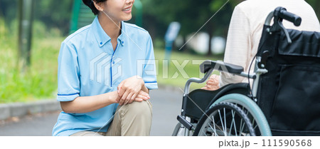 車椅子の高齢者と介護する若い女性 車椅子の高齢者と介護する若い女性 111590568