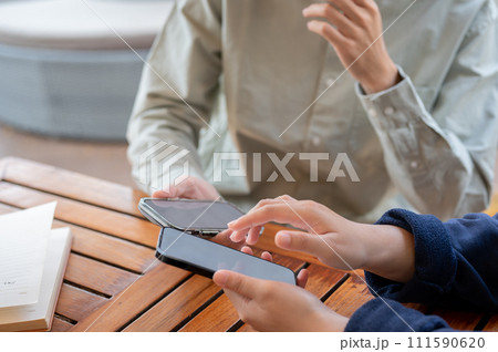 Two people sharing contact info or transferring files by bringing two smartphones close together. 111590620
