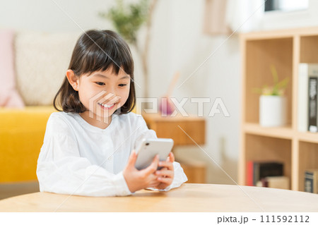 スマホを操作する小学生の女の子。 スマホを操作する小学生の女の子。 111592112