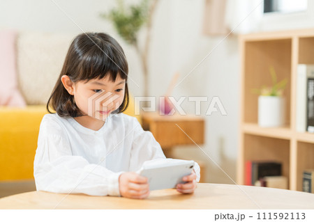 スマホを操作する小学生の女の子。 スマホを操作する小学生の女の子。 111592113