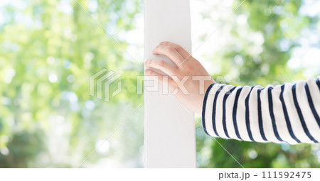 明るい屋内から白い枠の窓を開ける人物のポートレート 111592475
