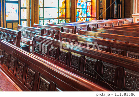 Empty wooden church benches of a Christian church. Blurry alter in the background. Selective focus. Concept of church service or empty churches. Empty wooden church benches of a Christian church. Blurry alter in the background. Selective focus. Concept of church service or empty churches. 111593586