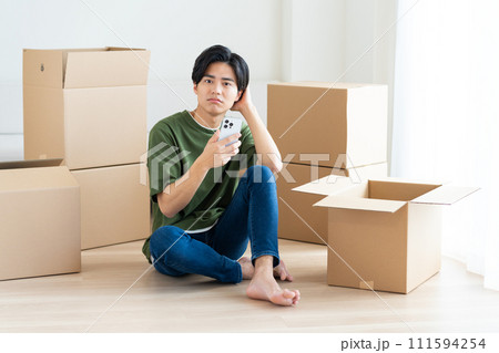 引っ越しでスマホを見る若い男性 引っ越しでスマホを見る若い男性 111594254