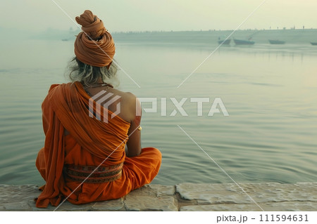 An old yogi was meditating on the bank of the Ganges River. It was quiet amidst the morning sunshine. Behind him is the view of Varanasi. It is a symbol of peace, tranquility and faith in Hinduism. 111594631