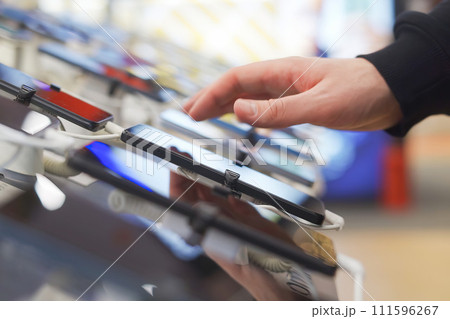 Hand of male buyer testing smartphone in electronics store 111596267
