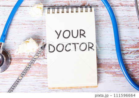 YOUR DOCTOR text is written on a notebook that lies on old vintage boards 111596664