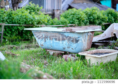 An old bathing tub is placed in the garden as a memento of a past life 111596696