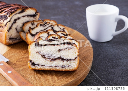 Fresh homemade bun with poppy seeds and mug of milk at dark background, breakfast concept 111598726