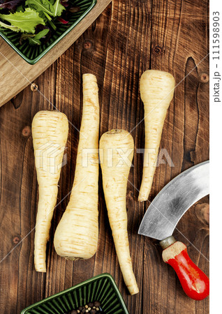 Raw parsnip roots on wooden table. Raw parsnip roots on wooden table. 111598903