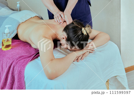 Back pain therapeutic with deep tissue massage, mobile massage therapist paid visit to young Caucasian woman. 111599397