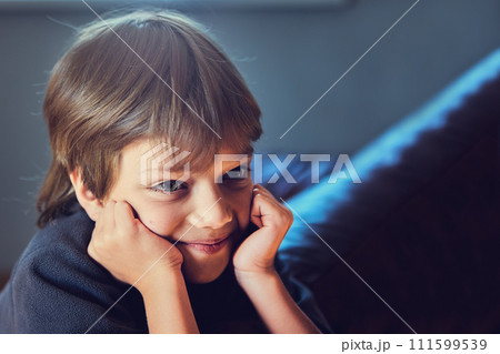 Young boy with his hands on his cheeks is looking in front of him. 111599539
