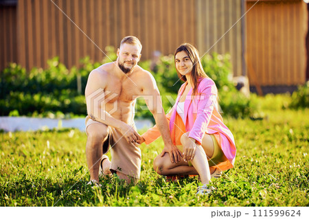 Married couple poses for photograph on front lawn, young white man and woman crouched in grass for photograph. Married couple poses for photograph on front lawn, young white man and woman crouched in grass for photograph. 111599624