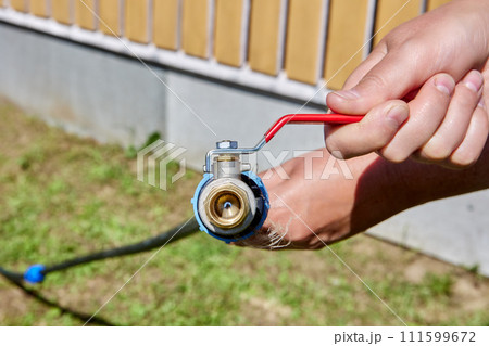 Brass ball valve with an activation lever is connected to polyethylene pipe with compression adapter fitting. Brass ball valve with an activation lever is connected to polyethylene pipe with compression adapter fitting. 111599672