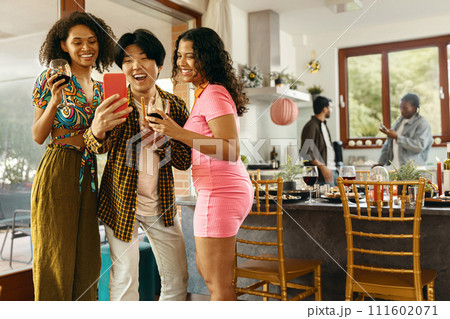 Smiling young friends taking selfie photo holding wine glasses on holiday dinner party at home 111602071