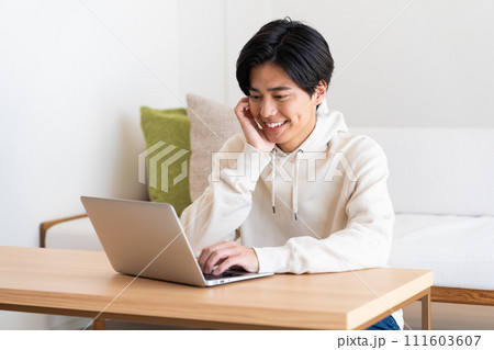 リビングでパソコンを使う若い男性 リビングでパソコンを使う若い男性 111603607