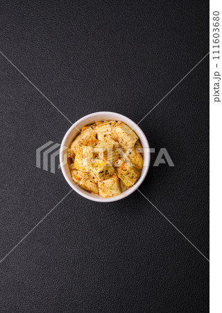 Delicious soft white feta cheese with salt, spices and herbs on a dark concrete background 111603680