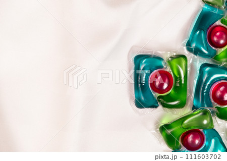 Lots of laundry pods capsule detergent on satin fabric, copy space for text. 111603702