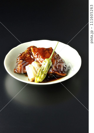 ブリの照り焼きと素揚げのししとうと長ねぎを黒背景で撮影 111605263