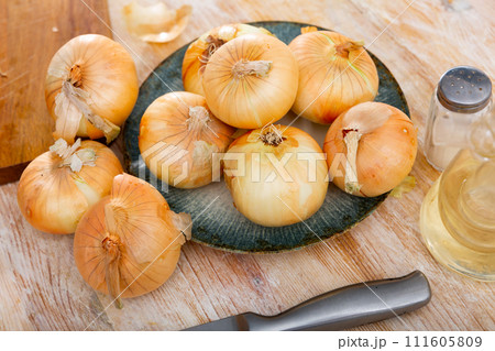 Yellow onion on kitchen table, food preparation 111605809