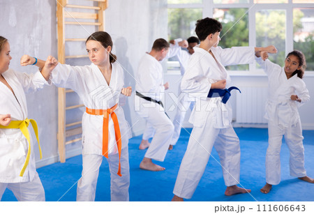 Two girls learn to throw punches and kicks in sparring for karate training in gym 111606643